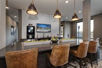 A large kitchen with a bar and chairs and a television